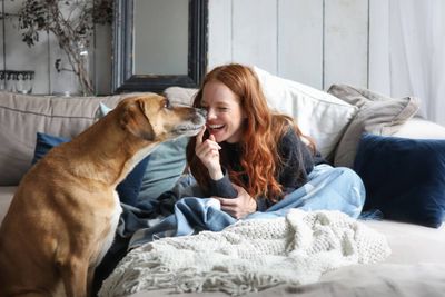 A woman laying on a couch with a dog next to her