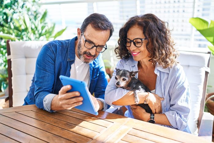 A man and woman sitting at a table with their puppy, picking pet insurance